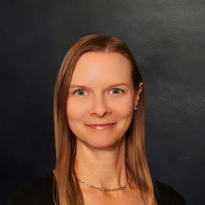 Chiropractor Julie Qualle Smiling In Front Of Dark Background